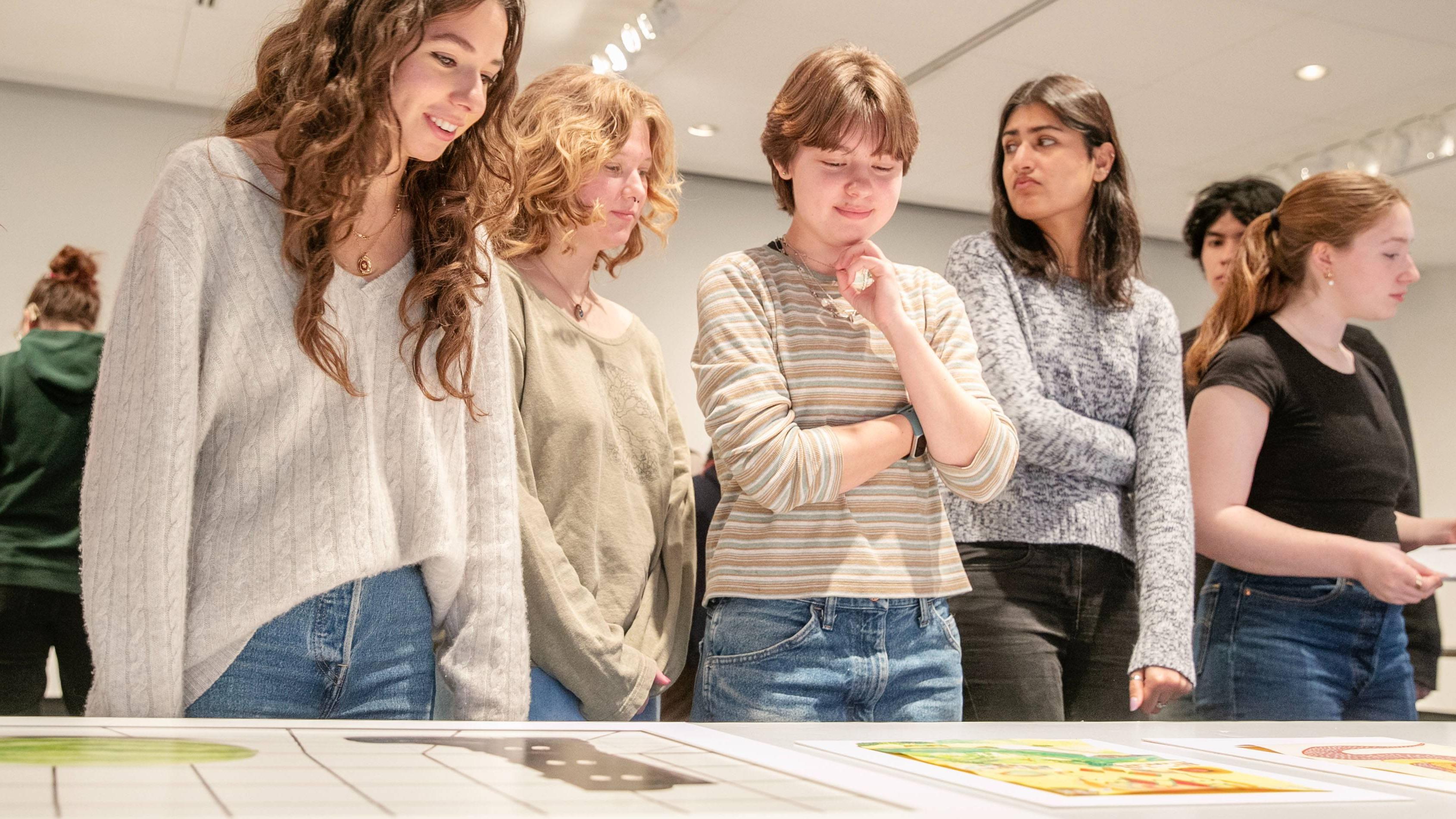 Skidmore students examine the art laid out on tables. 