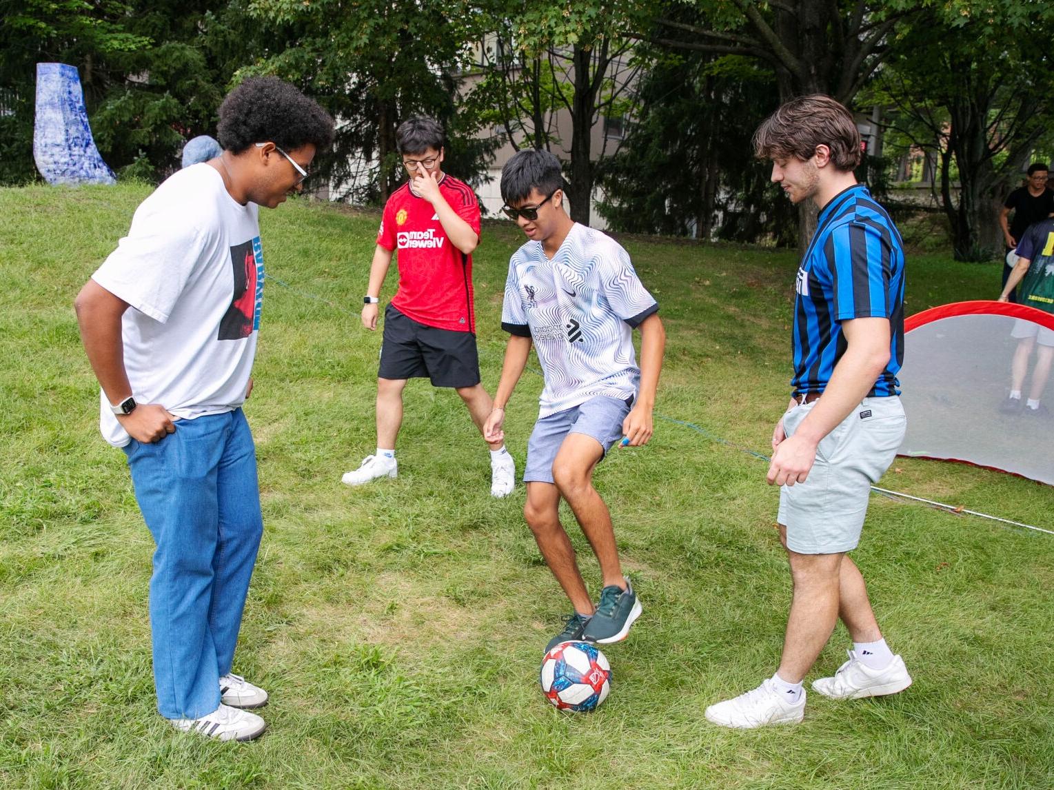 四个学生在火博体育的南草坪上踢足球.